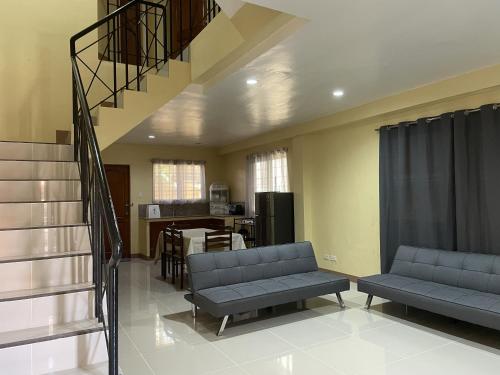 a living room with two couches and a staircase at Astra Bella Apartment - Unit 2 in Dumaguete