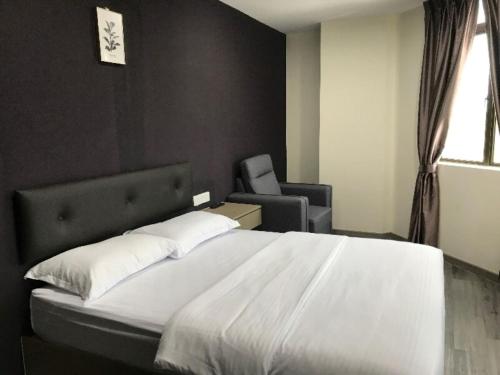 um quarto com uma grande cama branca e uma cadeira em Z Stay Inn Hotel 