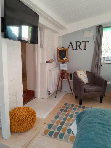 uma sala de estar com uma televisão de ecrã plano e uma cadeira em The Artist's Retreat em Calstock
