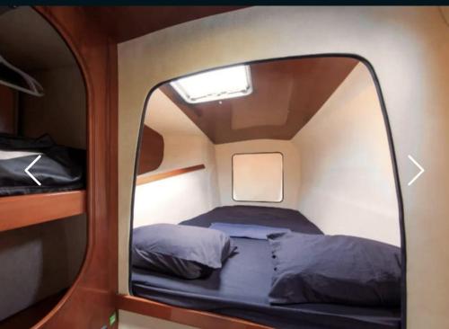 - un petit lit dans une petite chambre avec un miroir dans l'établissement TIVA Catamaran MOOREA, à Moorea