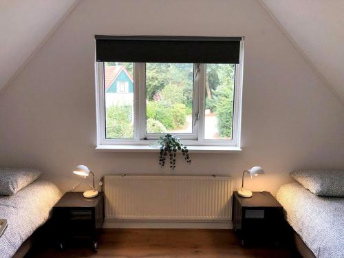 a attic room with two beds and a window at Bosvilla Lochem in Lochem