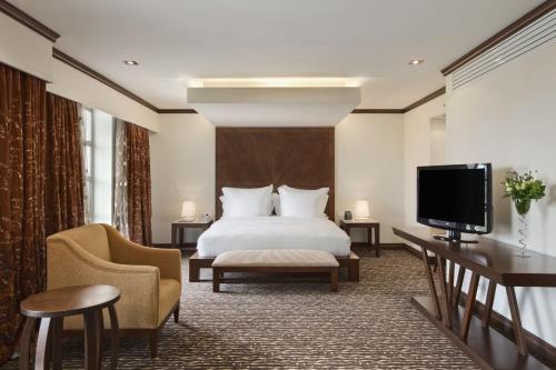 um quarto de hotel com uma cama e uma televisão de ecrã plano em Bisila Palace em Ciudad de Malabo