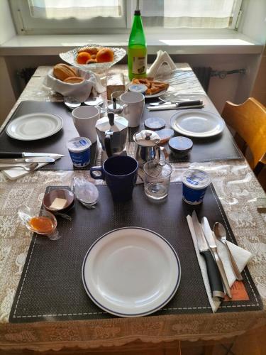 a table with white plates and utensils on it at le stanze di Saraswati in Salorno sulla Strada del Vino