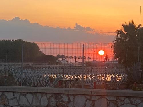 a sunset with the sun setting behind a fence at SoleeMare Barletta in Barletta