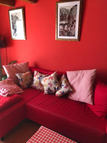 a red couch with pillows on a red wall at PUENTECUERVO in Pancorbo