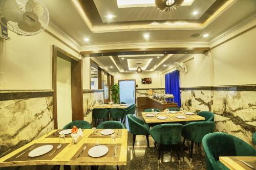 a restaurant with wooden tables and green chairs at SM Royal Stay Hotel - Near Bangalore international Airport in Bengaluru