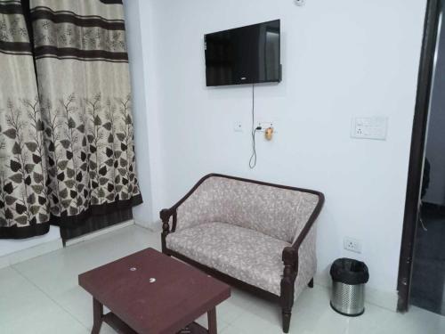 a chair and a table in a room with a tv at OYO Singh Homestay in New Delhi
