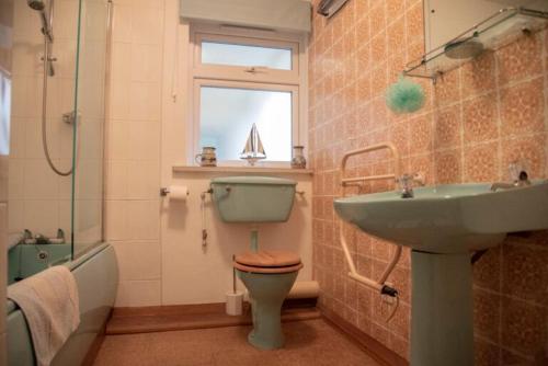 a bathroom with a sink and a toilet and a window at 3 Linkside, Thurlestone, South Devon, family home close to the beach in Thurlestone