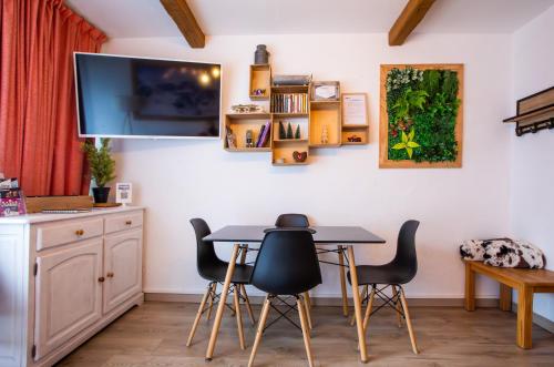- une salle à manger avec une table, des chaises et une télévision dans l'établissement Aux pieds des pistes, Les 2 Alpes, à Vénosc
