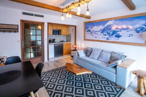 a living room with a blue couch and a kitchen at Aux pieds des pistes, Les 2 Alpes in Vénosc