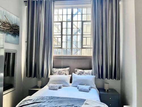 a bedroom with a bed and a window with blue curtains at Mocha Apartment next to Maboneng in Johannesburg
