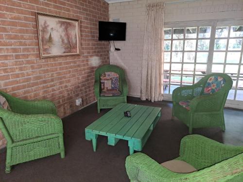 a living room with green chairs and a table at Shangrila-innibos Country Lodge in Hartbeespoort