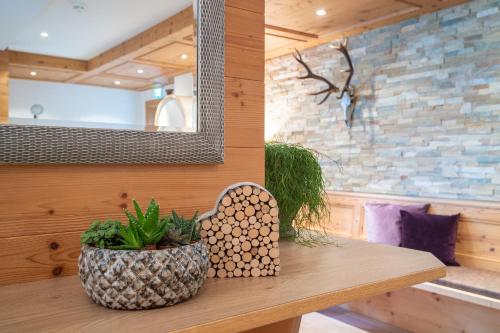 a wooden table with a plant and a mirror at Alphaus Aparthotel in Pertisau