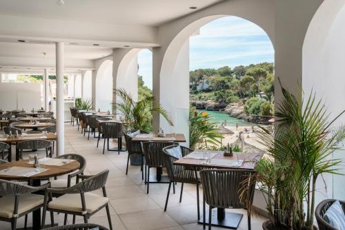 AluaSoul Mallorca Resort - Adults only في كالا ذاور: مطعم بطاولات وكراسي ومطل على نهر