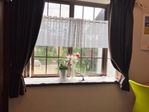 a window with a vase of flowers on a table at テラハウス国立 Terahouse Kunitachi in Kunitachi