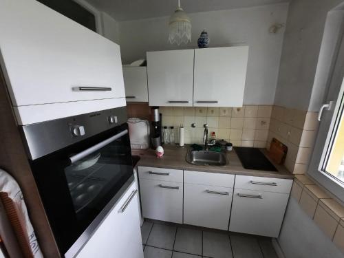 uma pequena cozinha com armários brancos e um lavatório em Oase der Ruhe und Entspannung em Bad Homburg vor der Höhe