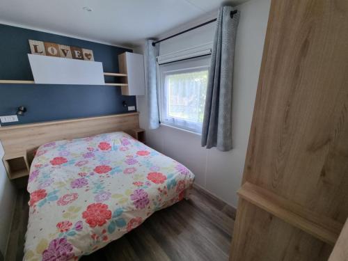 ein kleines Schlafzimmer mit einem Bett und einem Fenster in der Unterkunft Mobil-home 2023 RapidHome Panorama 3 chambres 6 vélos lave-vaisselle 2 piscines couvertes in Litteau