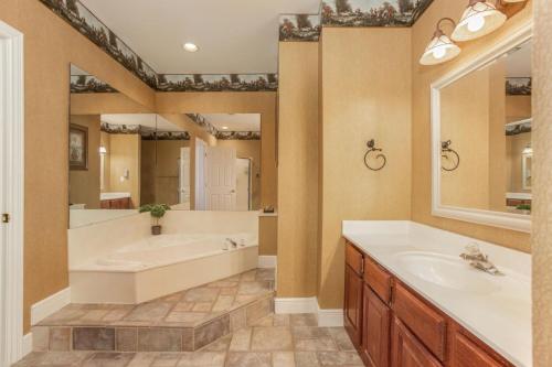 baño con bañera y espejo grande en Branson's Great Rock Retreat en Branson