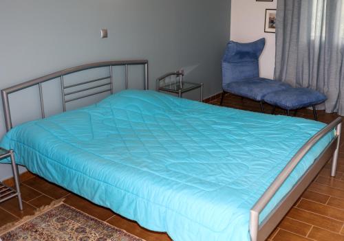 a bed with a blue comforter and a chair in a room at Agrilis Home in Filiatra