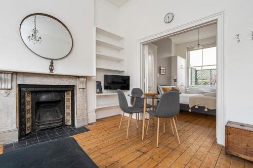 sala de estar con mesa, sillas y chimenea en JOIVY Chic flat with private terrace near Kensington Palace, en Londres
