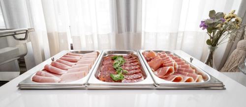 a table with three trays of meats and meatballs at Hotel Villa Virginia in Sabiñánigo