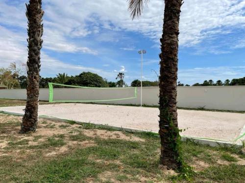 a tennis court with two palm trees and a volleyball net at Ap Remanso in Barreirinhas