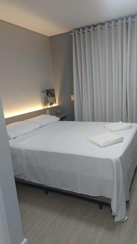 a bedroom with a large white bed with white curtains at Studio Vila Mariana in Sao Paulo