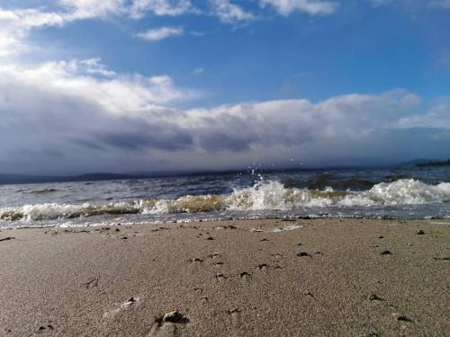 a beach with waves and footprints in the sand at Apartmán s terasou a výhledem na jezero Lipno in Kovářov