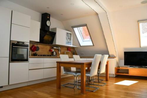 a kitchen with a wooden table and white cabinets at Stairway to Ljubljana Apartment in Ljubljana