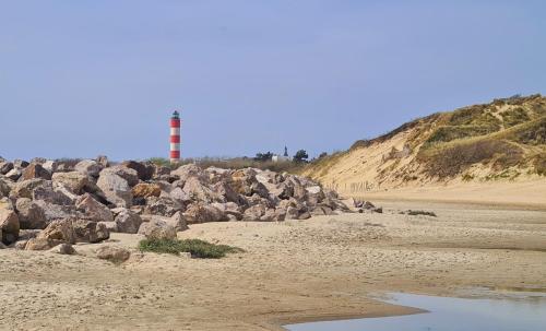un montón de rocas en una playa con un faro en el fondo en Studio 18 m2 à 100m de la mer, en Berck-sur-Mer