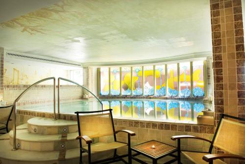 Zimmer mit einem Pool mit Stühlen und einer Badewanne in der Unterkunft Los Angeles Hotel & Spa in Granada