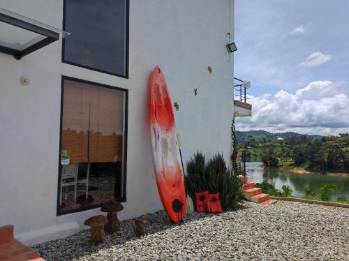 a red surfboard leaning against the side of a building at La Villa, Espectaculares vistas al lago Peñol-Guatape in Guatapé