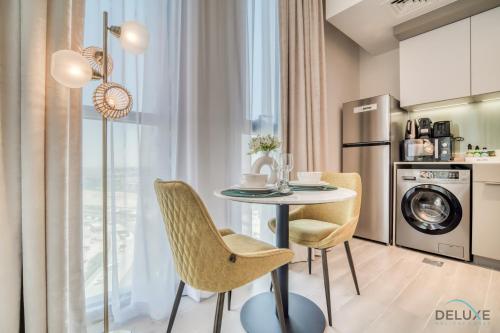 a kitchen and dining room with a table and chairs at Enchanting Studio at Mesk 1 Midtown Dubai Production City by Deluxe Holiday Homes in Dubai
