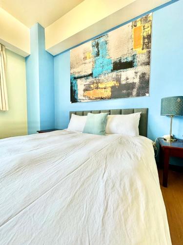 a bedroom with a white bed with a painting on the wall at 莫蘭狄 in Taichung