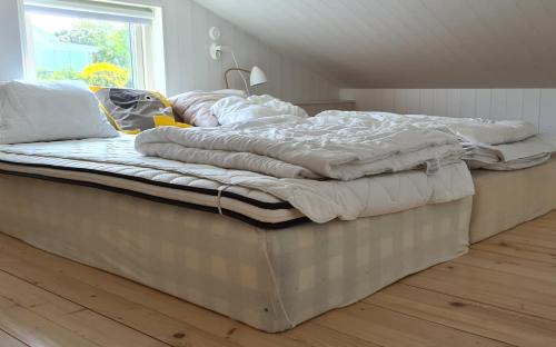 an unmade bed in a room with a window at Minihuset nära havet in Varberg