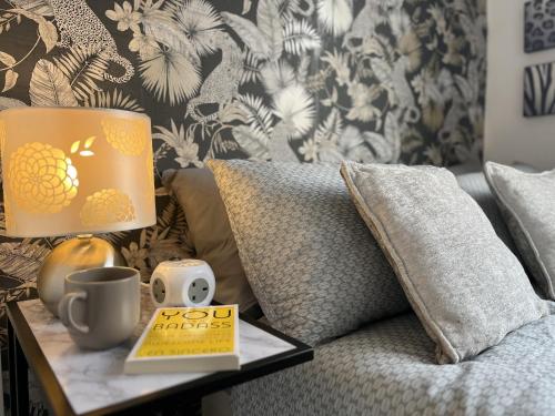 a book on a table next to a couch with a lamp at Modernised central Wigan townhouse sleeps up to 6 in Wigan