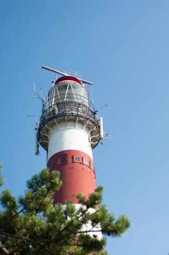 a red and white lighthouse with a tree in front of it at Breeze Ameland in Hollum