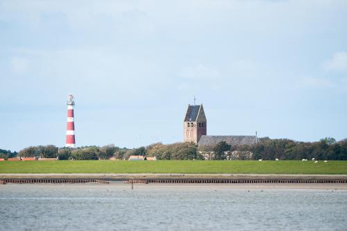 a lighthouse in the distance with the water and a building at Breeze Ameland in Hollum