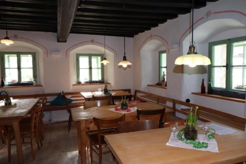 a restaurant with wooden tables and chairs and windows at Haidhäusl in Haidmühle