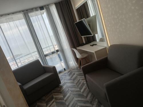 een hotelkamer met 2 stoelen, een bureau en een televisie bij СЛЪНЧЕВ ЗАЛИВ in Pomorie