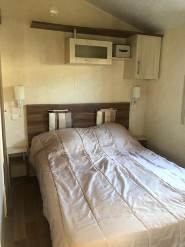 una camera da letto con un letto con una coperta bianca di mobilhome 582 Les Charmettes 3ch tout équipé a Les Mathes