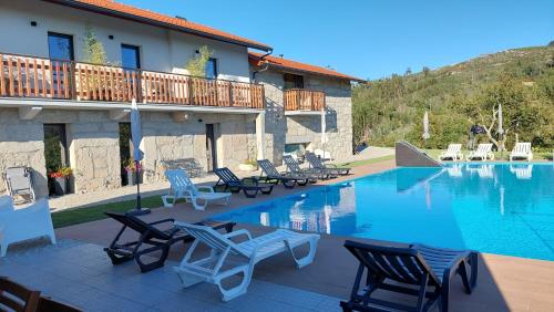 a resort with a pool with chairs and a building at Quinta de Cerdeiró in Mões