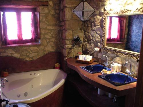 y baño con 2 lavabos, bañera y espejo. en Casa Rural Petita d'en Chinascas, en Vespellà