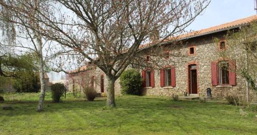 un bâtiment en pierre avec des fenêtres rouges et un arbre dans l'établissement Gites dans le parc classé du Martreil, à Sainte-Christine