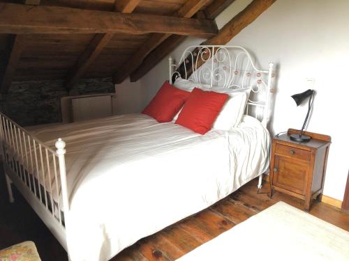 a bedroom with a white bed with red pillows at Casa Tula in Ortigueira