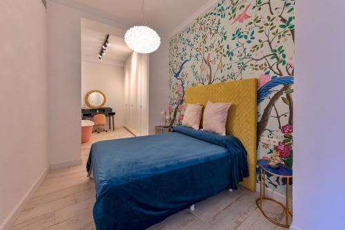 1 dormitorio con cama azul y pared de flores en Casa Carmen Murcia, en Murcia