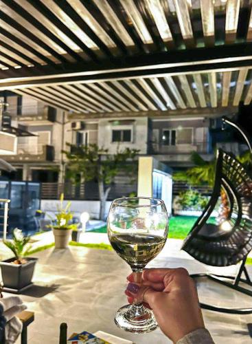 a person holding a glass of wine on a table at StayInn Luxury Apartments in Nea Kalikratia