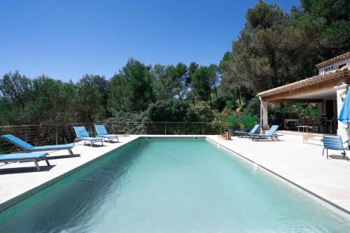 une piscine avec des chaises longues bleues et une piscine dans l'établissement Villa climatisée avec vue en pleine pinède aixoise, à Saint-Marc-Jaumegarde
