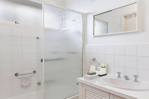 a white bathroom with a sink and a shower at Location, Location, Location! Walk to beach & town in Mornington