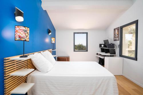 - une chambre avec un lit blanc et un mur bleu dans l'établissement Villa climatisée avec vue en pleine pinède aixoise, à Saint-Marc-Jaumegarde